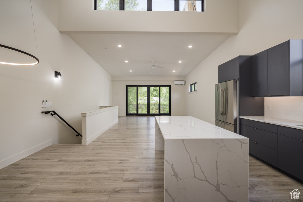 Kitchen with high end refrigerator, modern cabinets, a kitchen island, recessed lighting, and dark cabinets