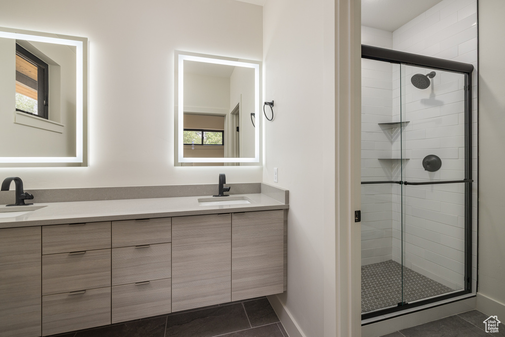 Bathroom featuring double vanity, tile patterned flooring, a stall shower, and baseboards