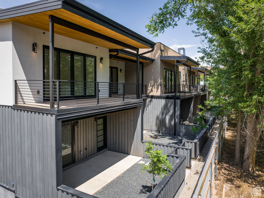 Rear view of house featuring stucco siding and a balcony