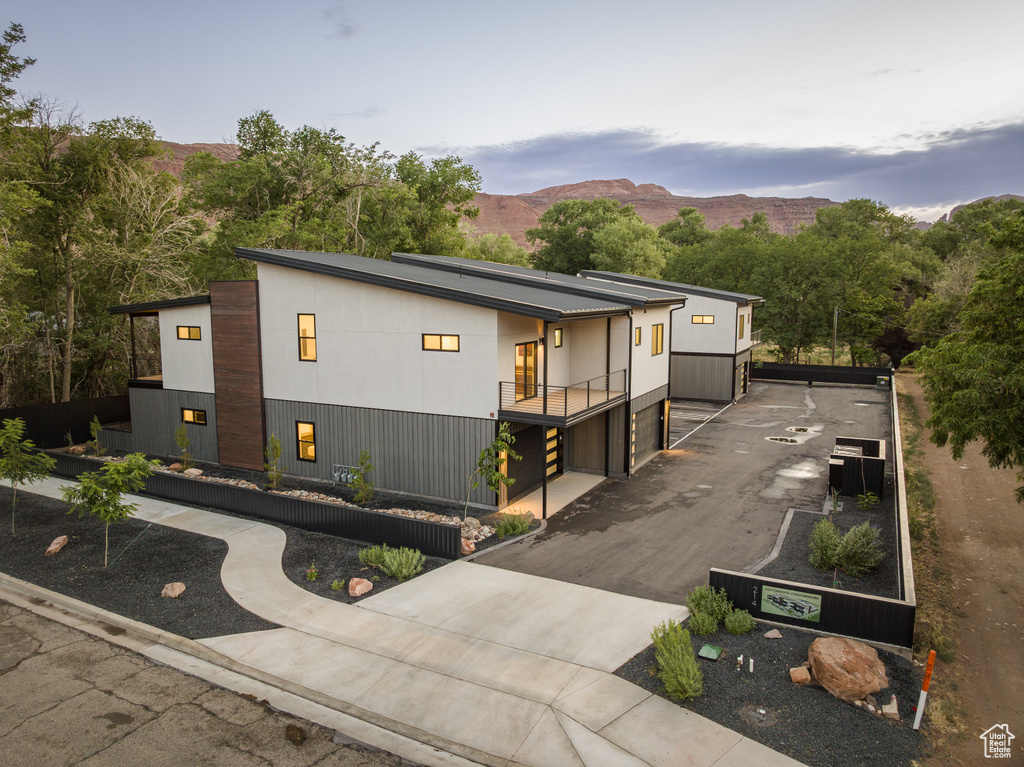 Contemporary house featuring a mountain view, a balcony, and asphalt driveway