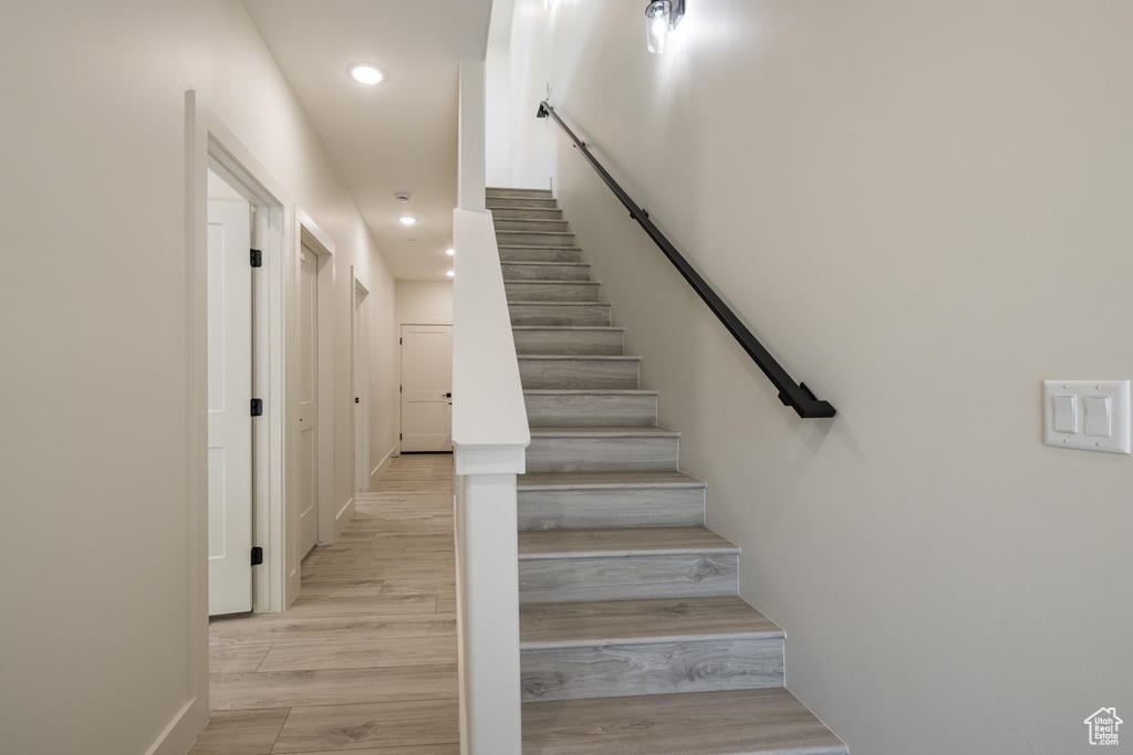 Staircase with recessed lighting and wood finished floors