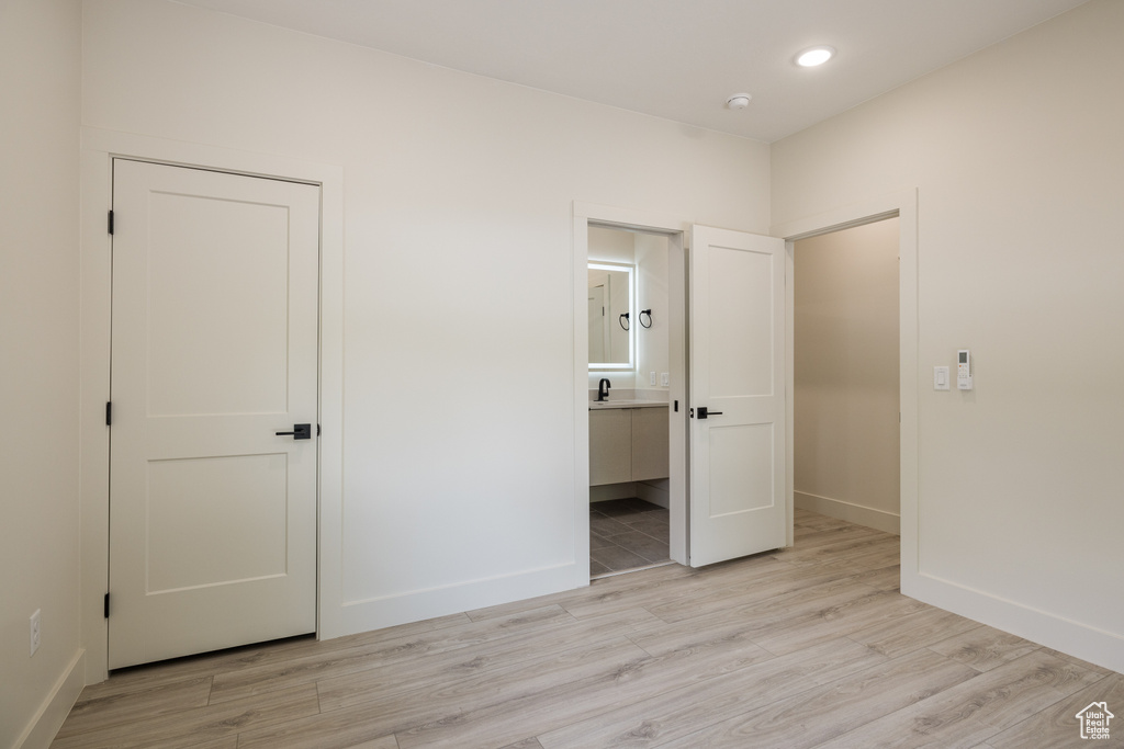 Unfurnished bedroom with light wood-style flooring, baseboards, connected bathroom, recessed lighting, and a sink
