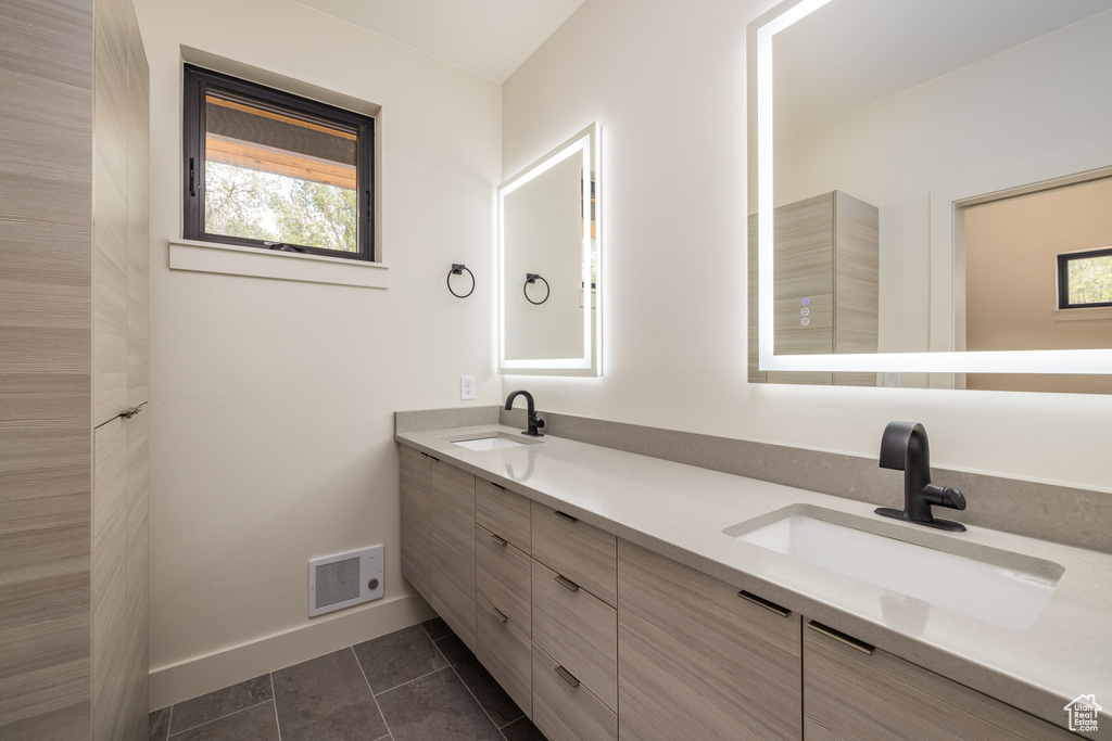 Bathroom with double vanity, baseboards, and tile patterned floors