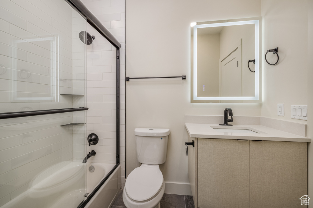 Full bathroom featuring toilet, vanity, and bath / shower combo with glass door