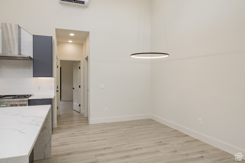 Unfurnished dining area featuring light wood-type flooring, baseboards, and an AC wall unit
