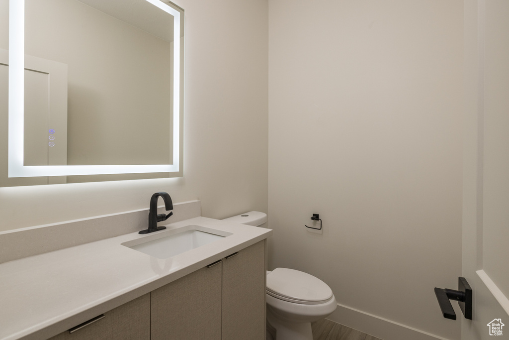 Bathroom with toilet, vanity, and baseboards
