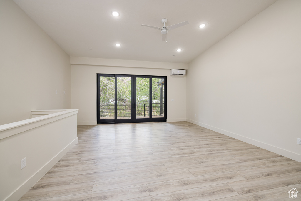 Unfurnished room with a wall mounted air conditioner, a ceiling fan, recessed lighting, baseboards, and light wood-style flooring