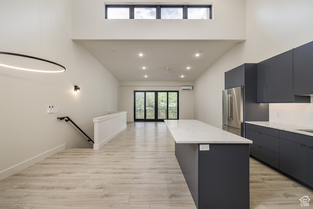 Kitchen featuring high end fridge, a towering ceiling, modern cabinets, a kitchen island, and light wood finished floors