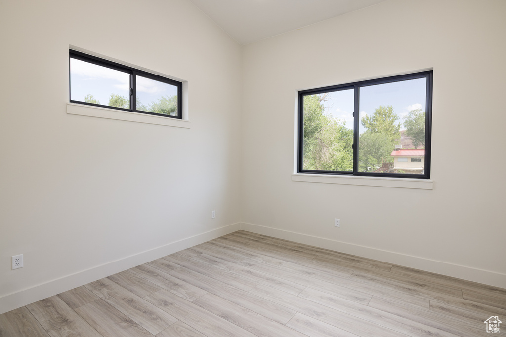 Spare room with healthy amount of natural light, baseboards, and light wood-style floors