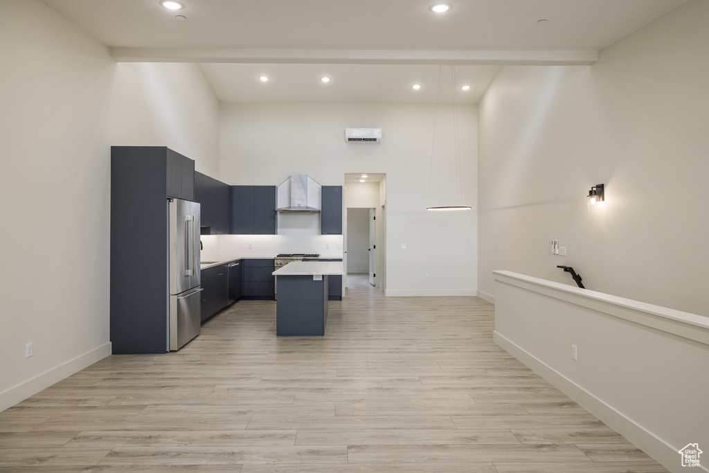 Kitchen featuring stainless steel fridge, a high ceiling, recessed lighting, light countertops, and light wood-style floors
