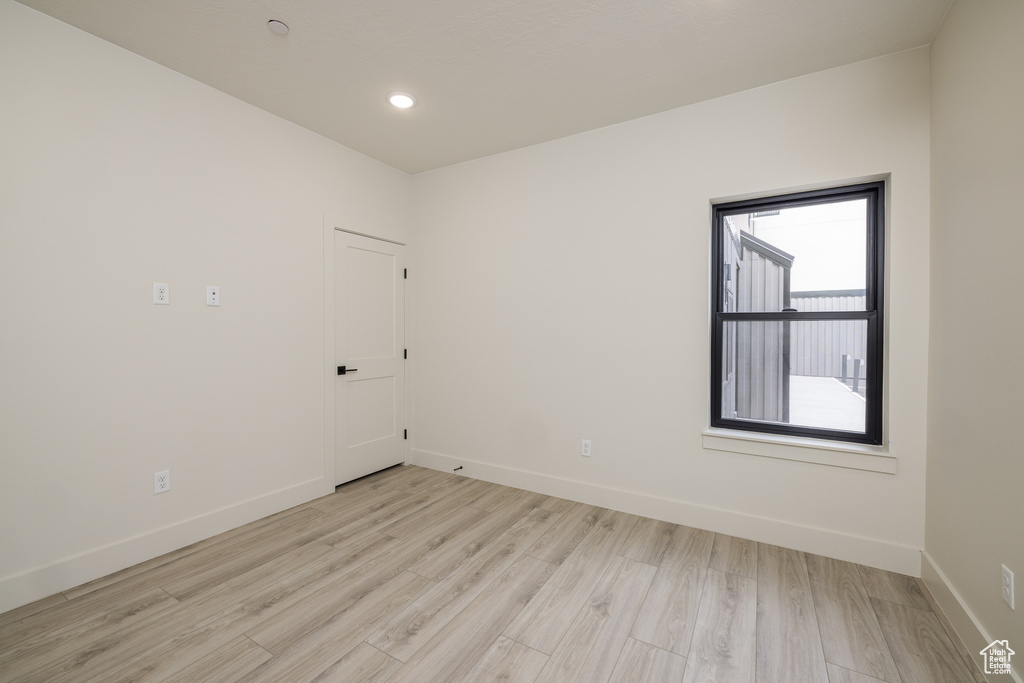 Spare room featuring light wood-type flooring, baseboards, and recessed lighting
