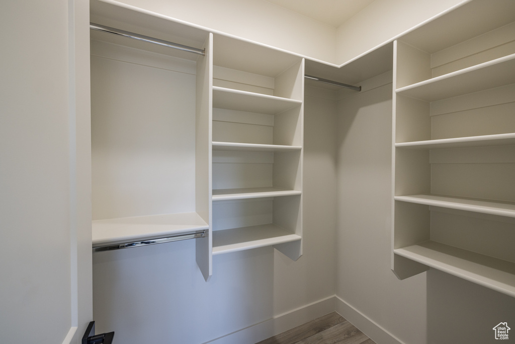 Walk in closet with dark wood-type flooring
