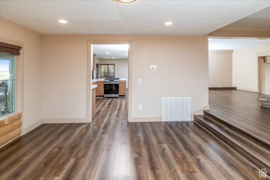 Spare room with dark wood-type flooring, a textured ceiling, and recessed lighting