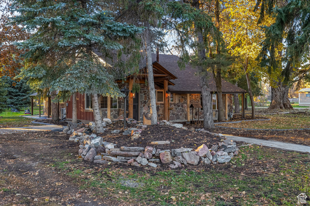 View of front of property featuring roof with shingles and stone siding