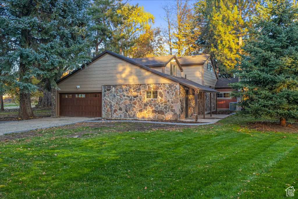 View of home\'s exterior with a lawn, a garage, asphalt driveway, and stone siding