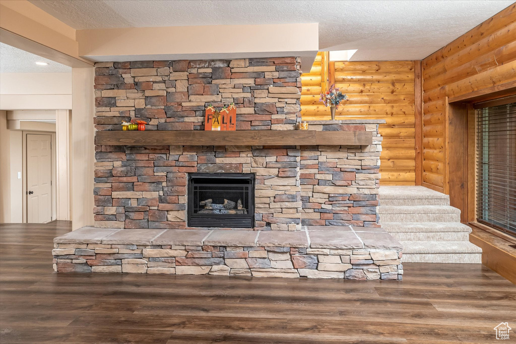 Detailed view of rustic walls, a textured ceiling, wood finished floors, and a fireplace