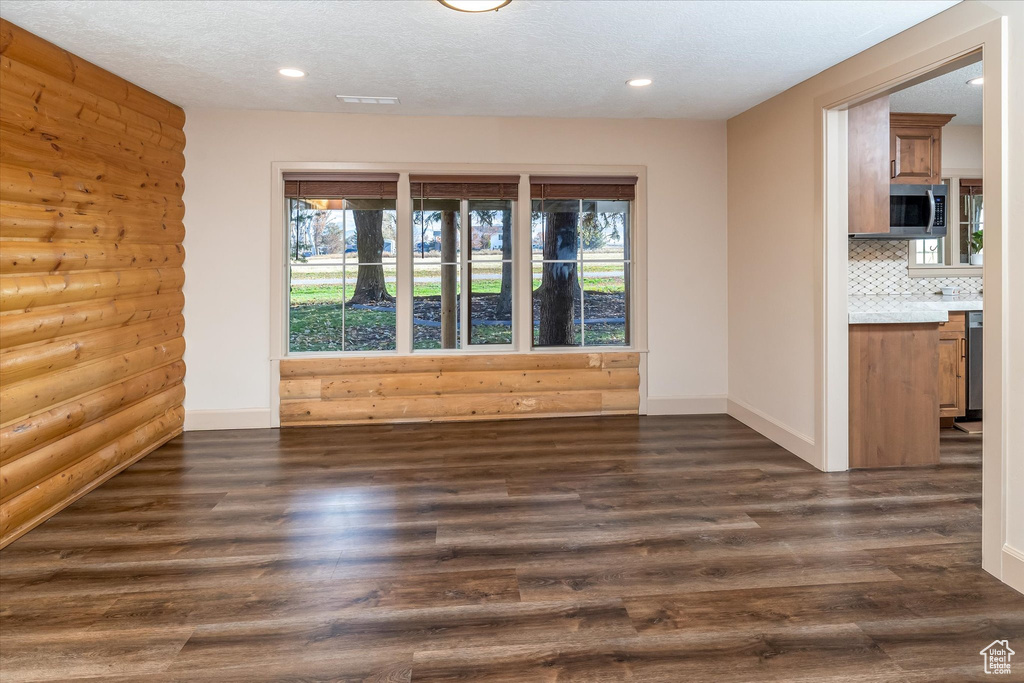 Unfurnished room featuring plenty of natural light, dark wood-style flooring, recessed lighting, and a textured ceiling