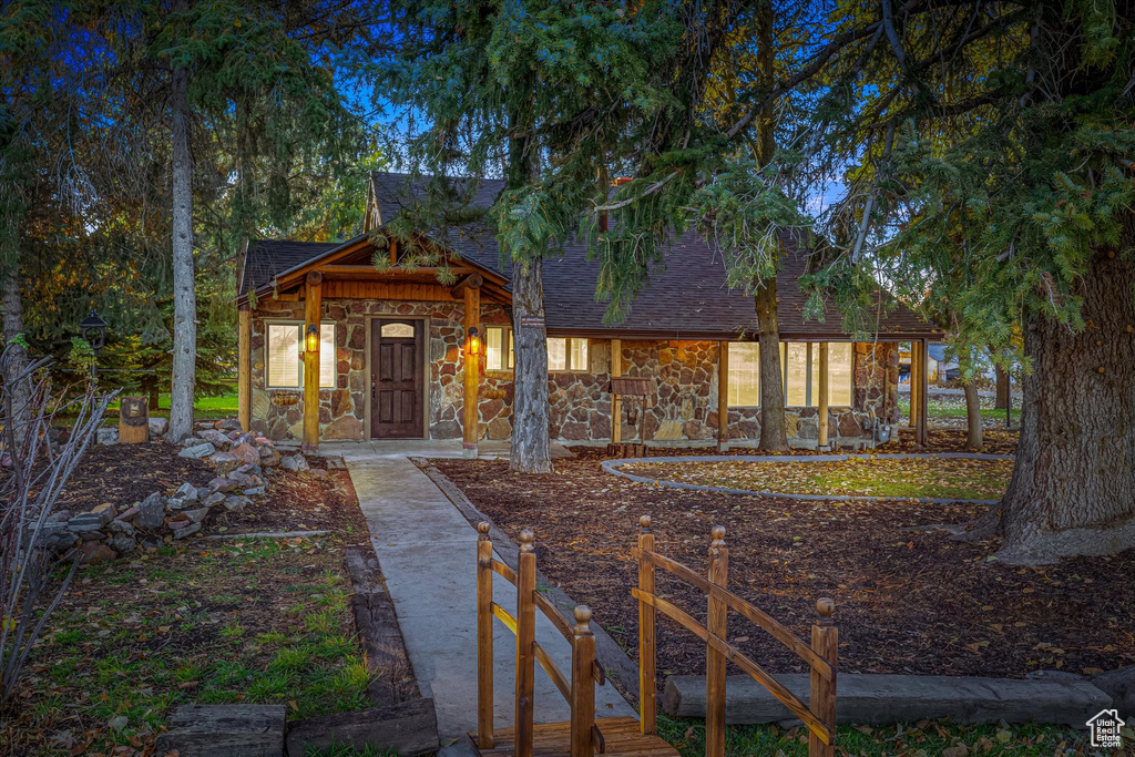 Rustic home featuring stone siding and roof with shingles