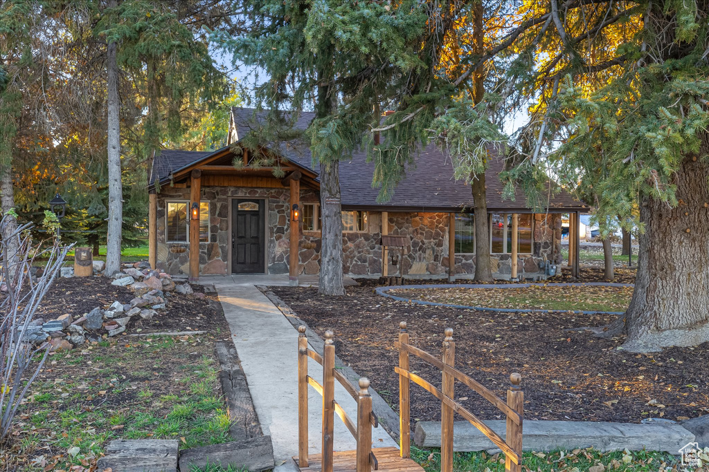 View of front of home with stone siding and a shingled roof