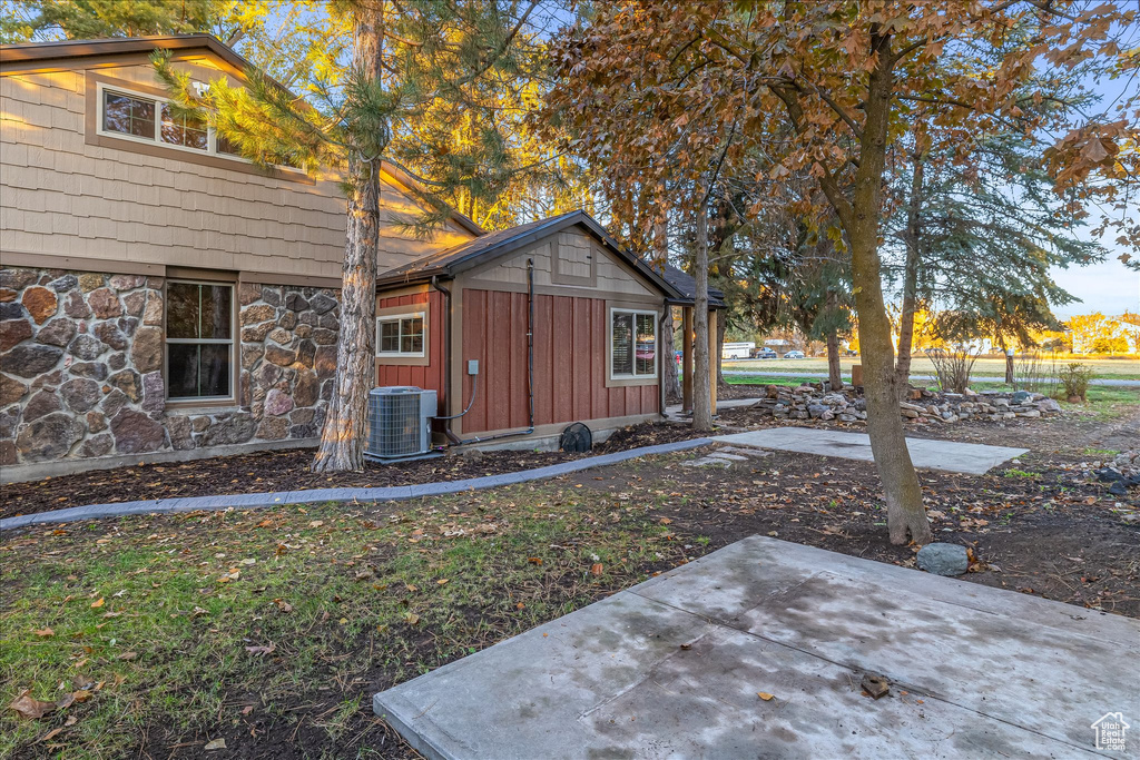 View of front of home with board and batten siding, a patio, and stone siding