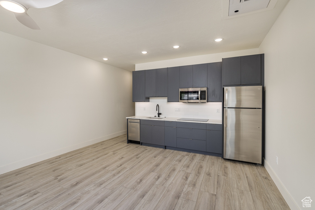 Kitchen featuring stainless steel appliances, light wood-style flooring, a sink, light countertops, and recessed lighting