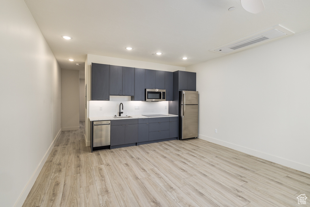 Kitchen featuring appliances with stainless steel finishes, light wood-style floors, a sink, recessed lighting, and light countertops