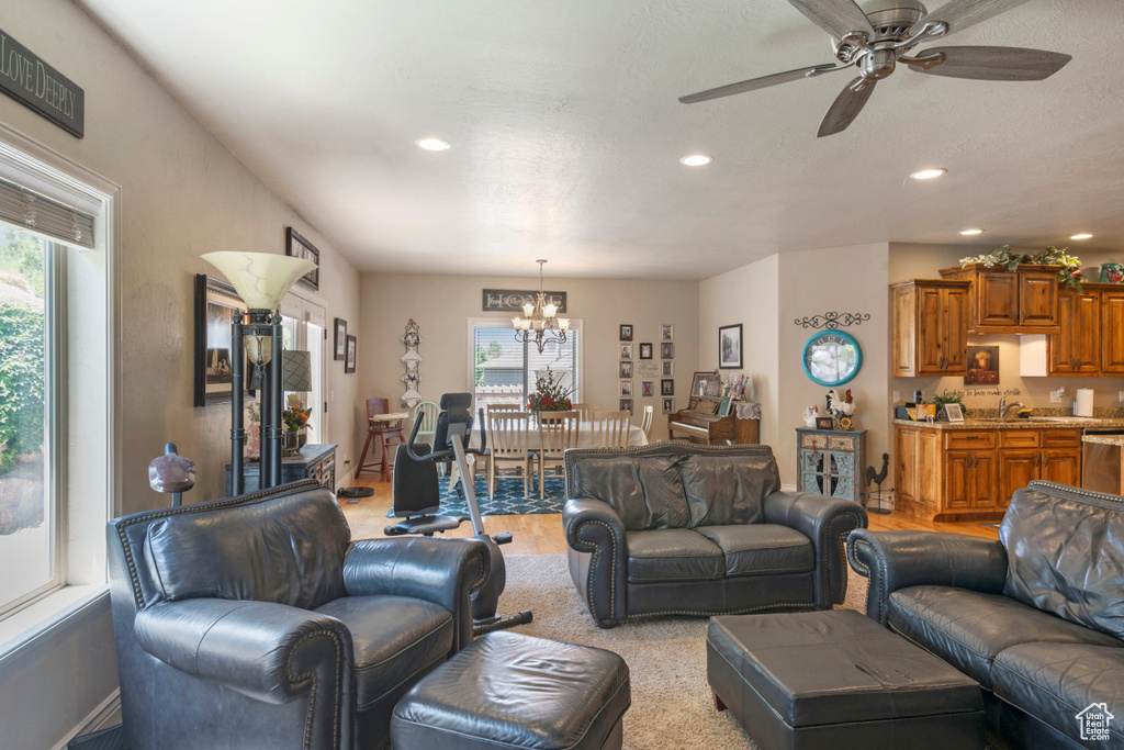 Living area with a chandelier, recessed lighting, light wood-type flooring, and a ceiling fan