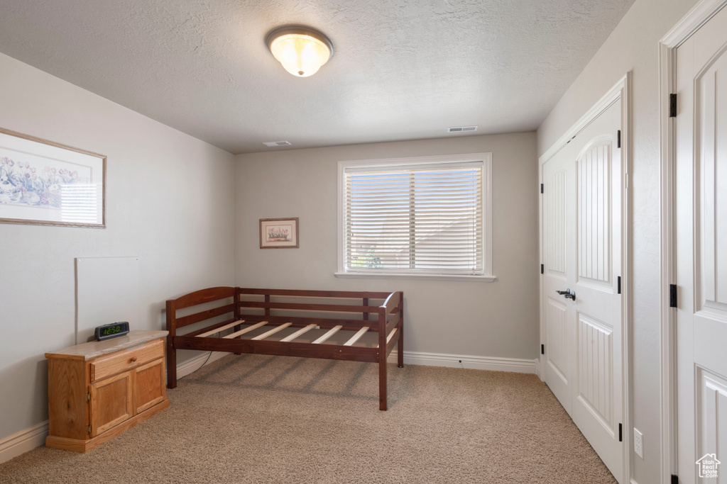Bedroom featuring light carpet and a textured ceiling