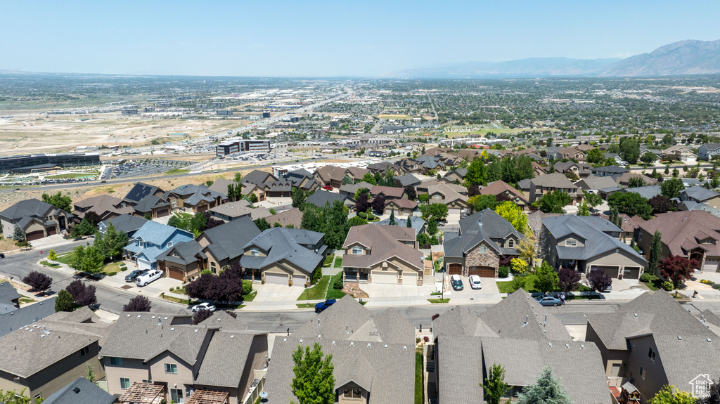 Aerial view of property and surrounding area featuring a mountainous background and nearby suburban area
