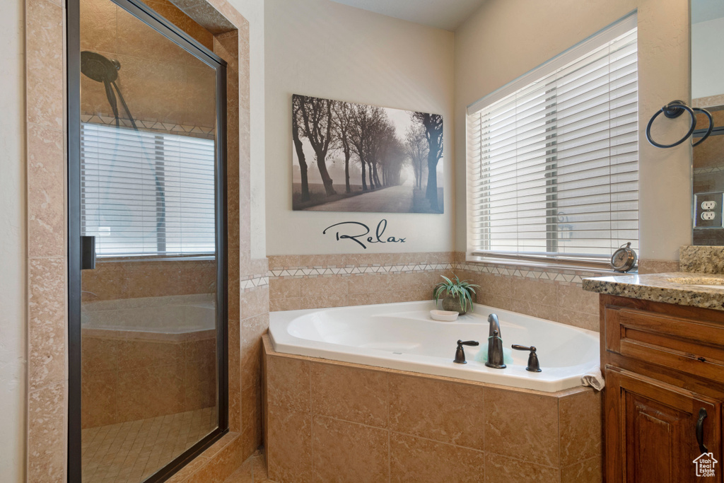 Full bathroom featuring vanity, a garden tub, and a stall shower