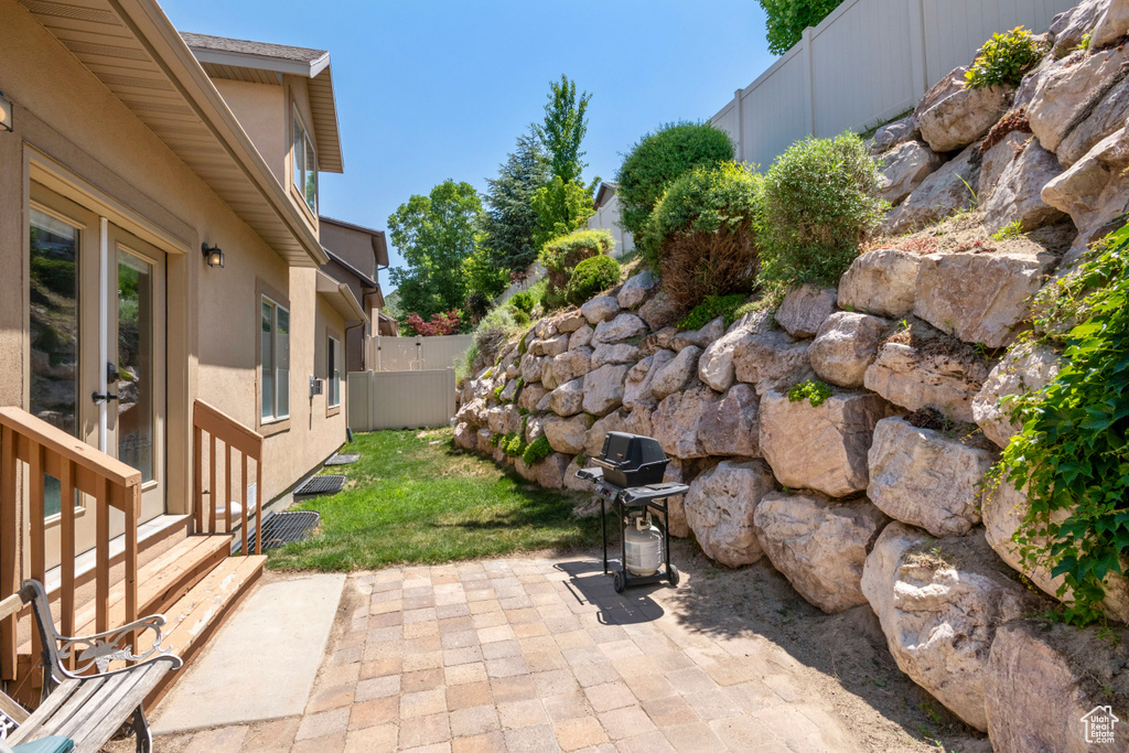 Fenced backyard featuring a patio area and a grill