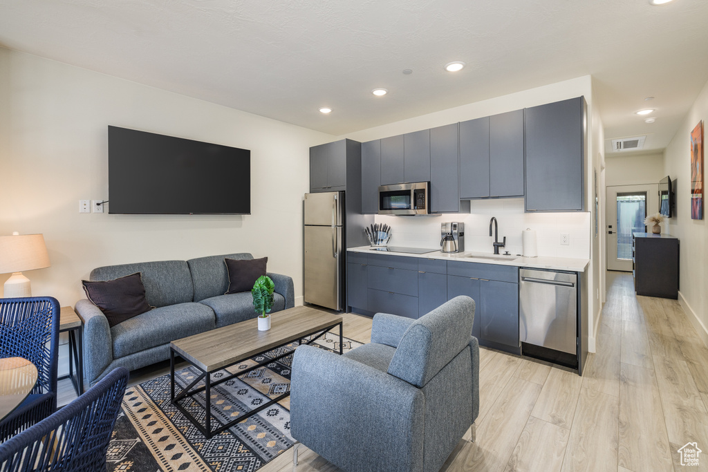 Living room with light wood finished floors, recessed lighting, and baseboards