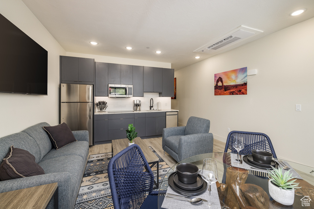 Living room with light wood-style floors, recessed lighting, and baseboards