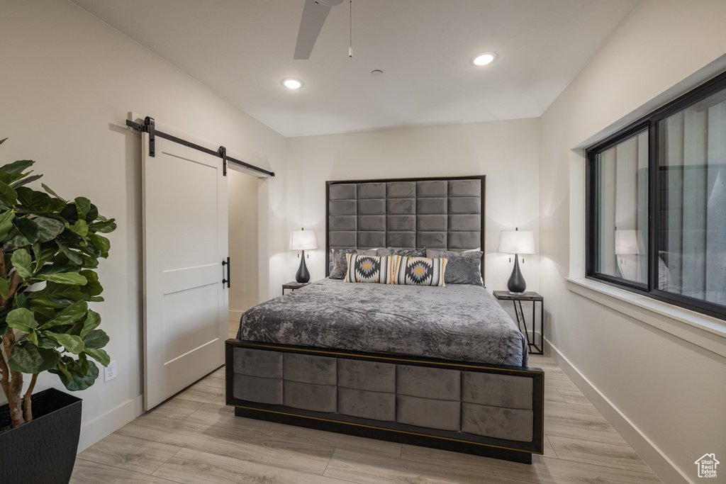 Bedroom with a barn door, baseboards, light wood-type flooring, recessed lighting, and ceiling fan