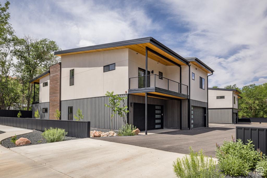 View of front of home featuring a balcony, a garage, and driveway