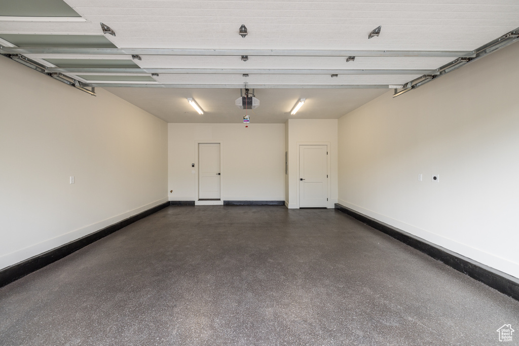 Garage featuring a garage door opener and baseboards