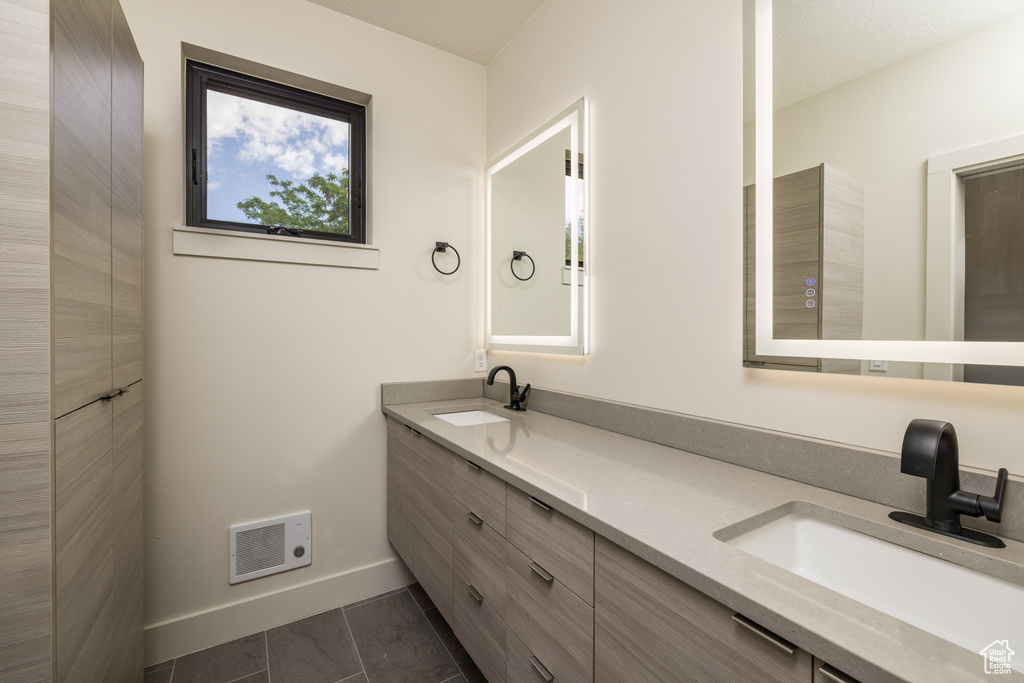 Bathroom featuring double vanity, baseboards, and tile patterned floors