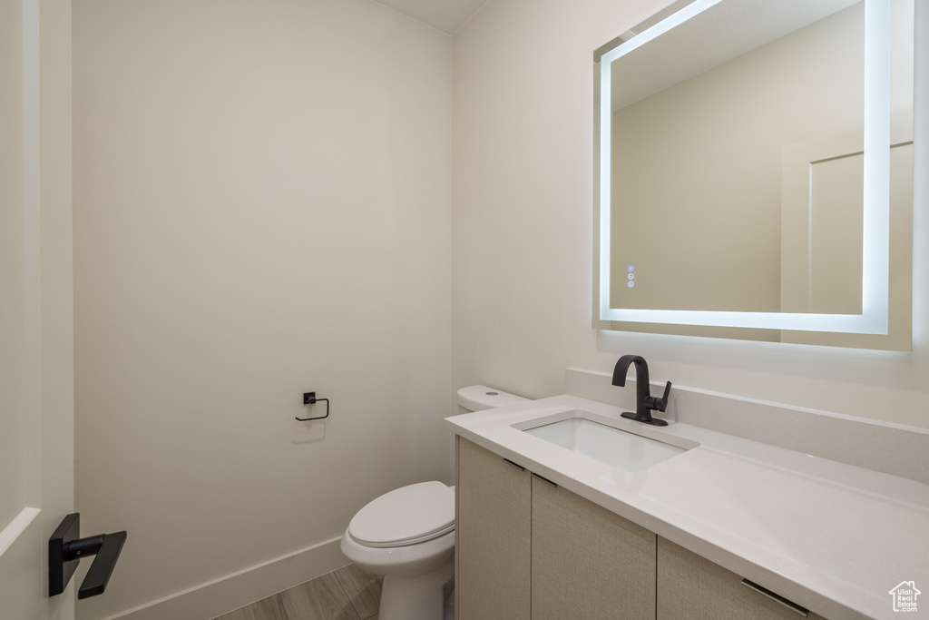 Bathroom featuring vanity, toilet, and baseboards