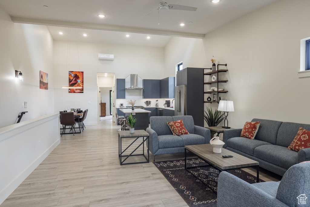 Living area with high vaulted ceiling, a ceiling fan, recessed lighting, and light wood-style floors