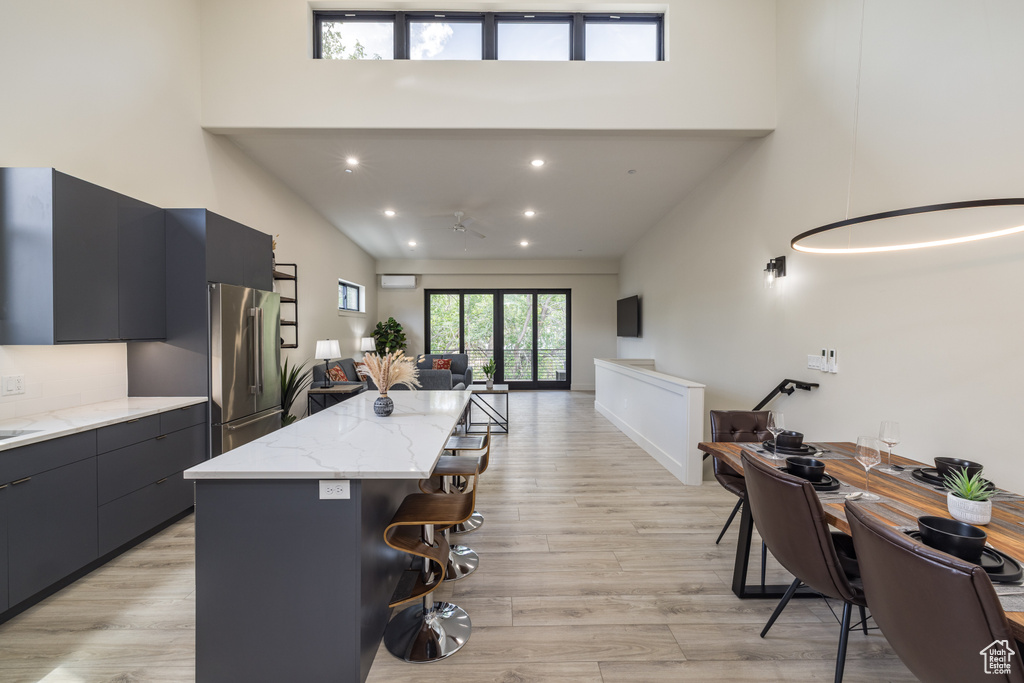 Kitchen featuring high end refrigerator, a towering ceiling, a breakfast bar area, modern cabinets, and open floor plan
