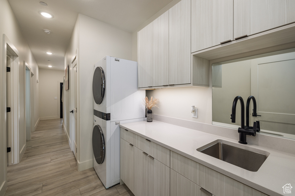 Laundry area with stacked washing machine and dryer, recessed lighting, light wood-style flooring, and baseboards