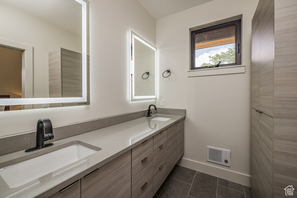 Bathroom featuring double vanity, baseboards, and tile patterned flooring