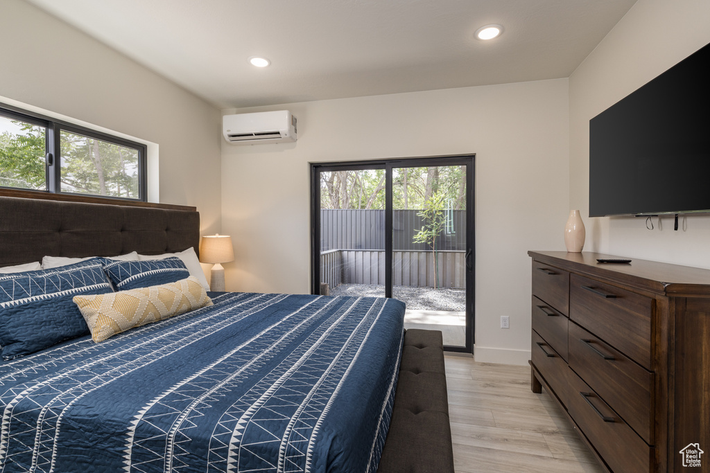 Bedroom with a wall mounted AC, multiple windows, access to outside, recessed lighting, and light wood-style flooring