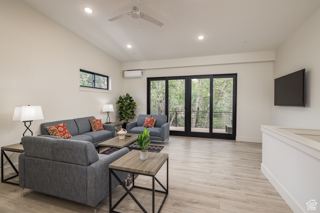Living area with a wall mounted AC, plenty of natural light, recessed lighting, baseboards, and light wood-style floors