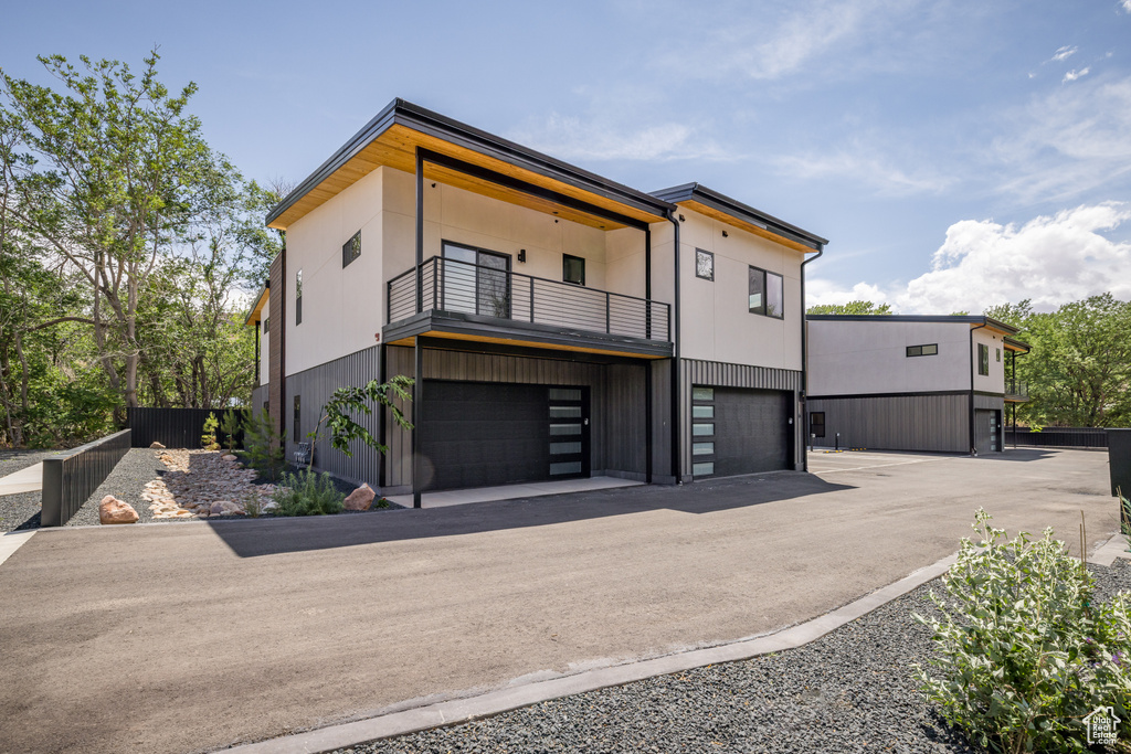 Contemporary house with a balcony, an attached garage, and asphalt driveway