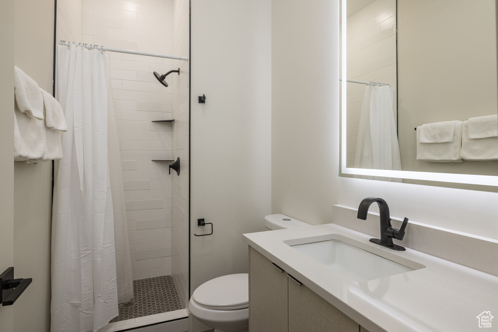 Full bath with toilet, vanity, and a stall shower