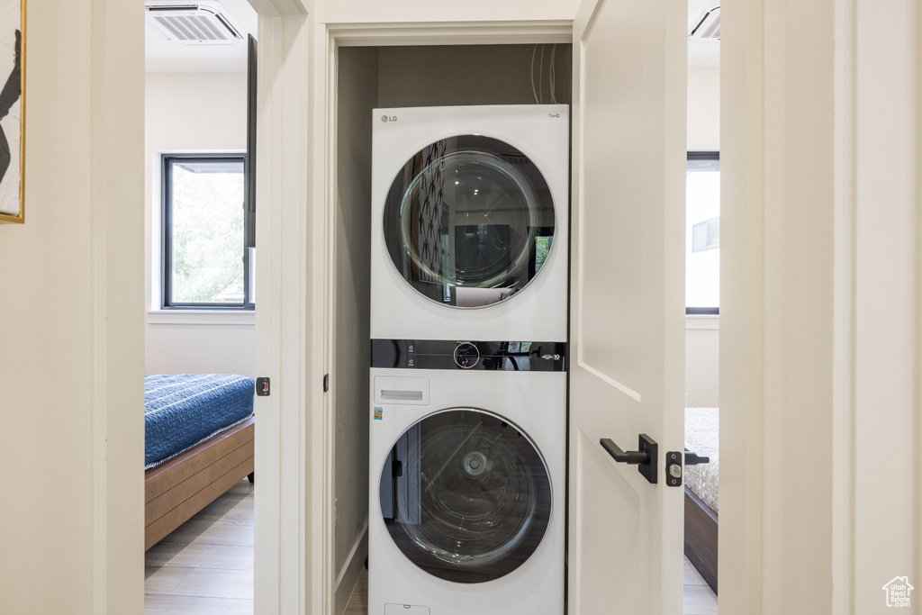 Laundry area with stacked washer / dryer and wood finished floors