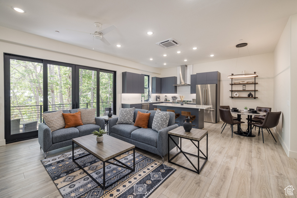 Living room with recessed lighting, ceiling fan, light wood-style floors, and baseboards