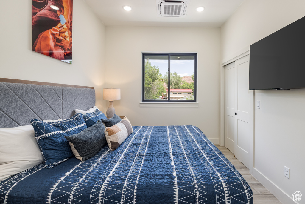Bedroom featuring wood finished floors, recessed lighting, baseboards, and a closet
