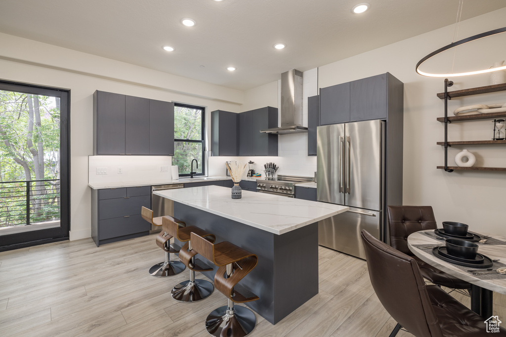 Kitchen featuring stainless steel appliances, wall chimney range hood, modern cabinets, and recessed lighting